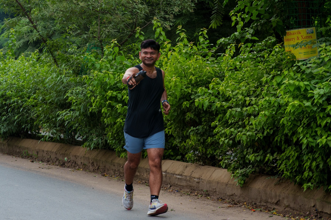 A lone runner smiling mid-stride along a quiet, tree-lined street in the early morning