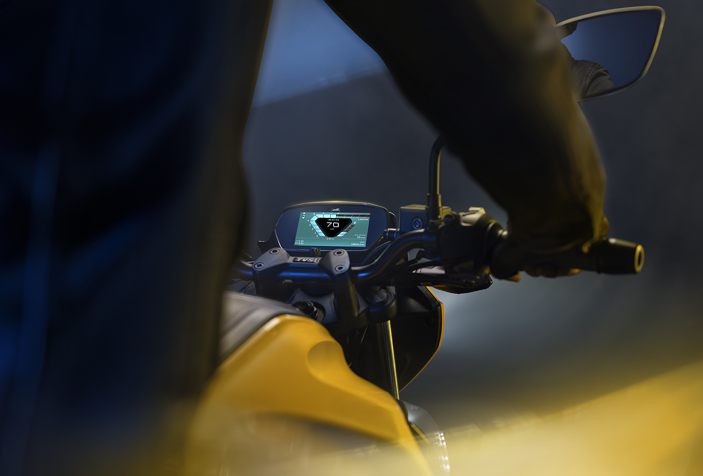 Rider's-eye view over the handlebars of the TVS Raider, instrument cluster reading 70 km/h