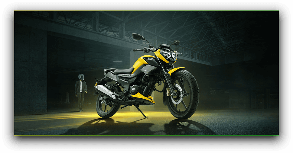 TVS Raider parked in a dim warehouse space, headlight lit, a rider's silhouette walking away in the background